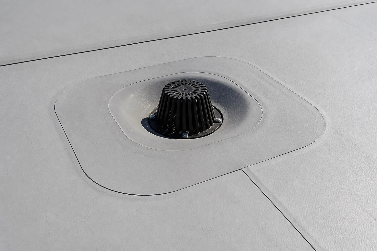 Close detail of a low-slope roof membrane seam and flashing at a roof drain