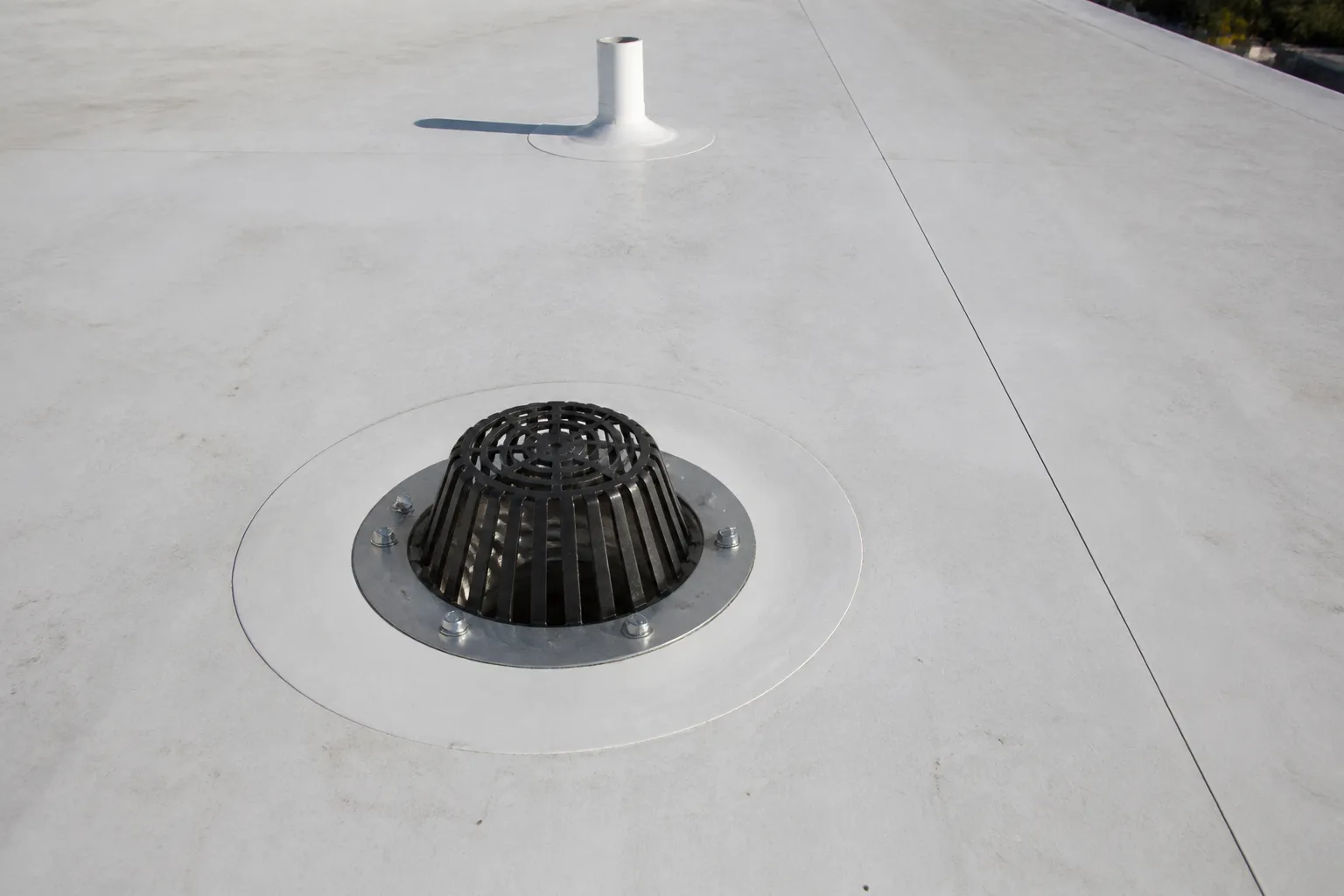 Close view of a commercial roof drain, membrane seam, and penetration flashing.