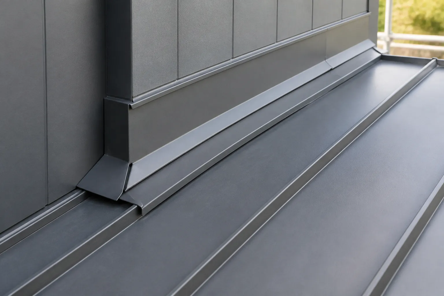 Raised standing-seam metal roof panel and folded flashing at a roof-to-wall transition