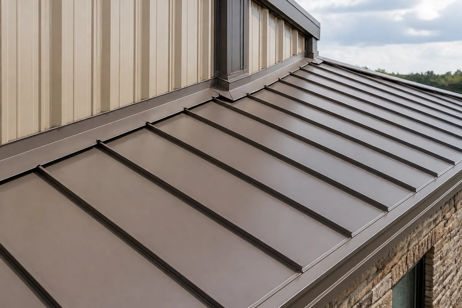 Close view of muted bronze standing-seam roof panels and flashing at a wall transition