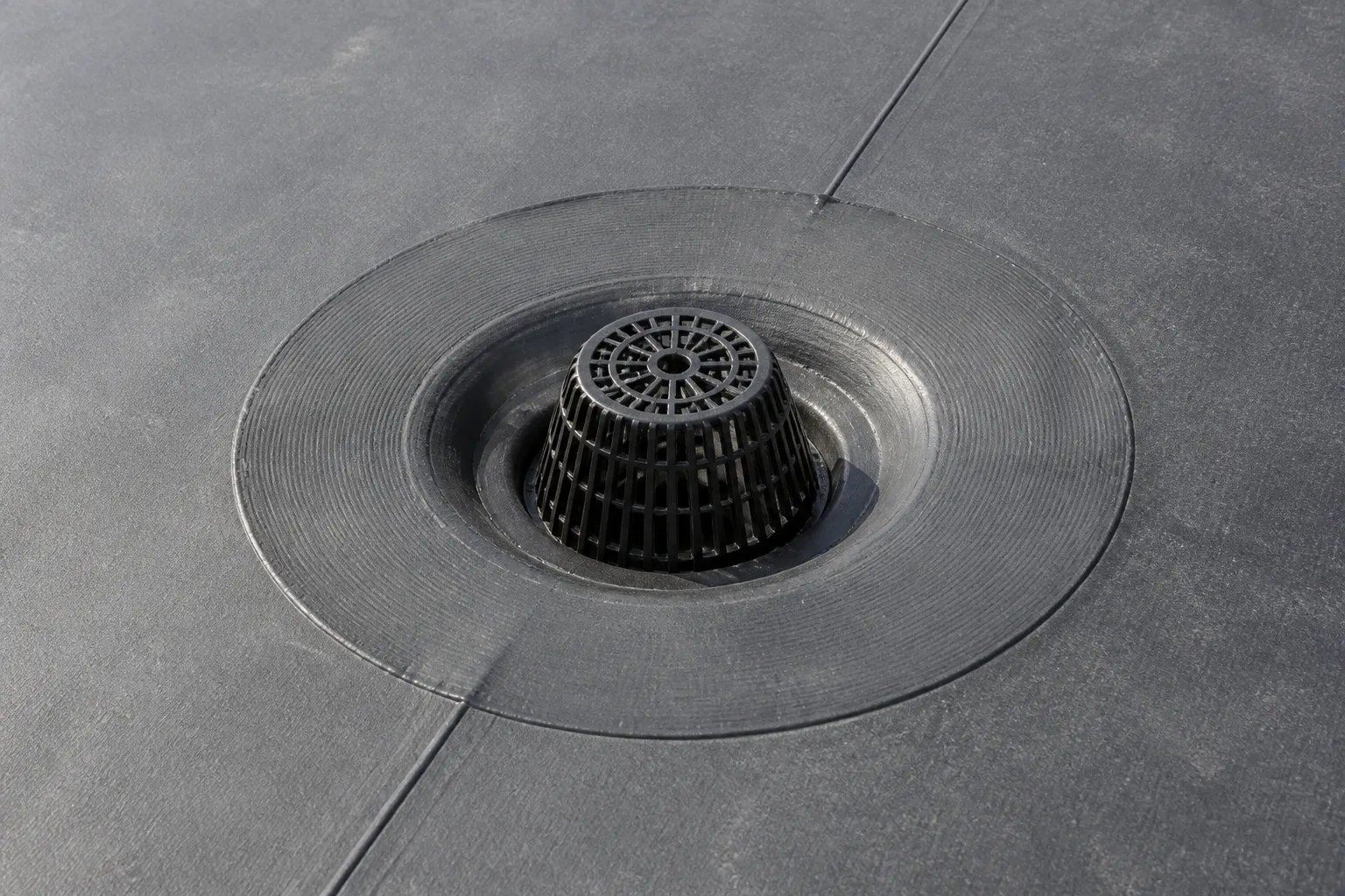 Commercial roof drain with membrane flashing and an adjacent seam