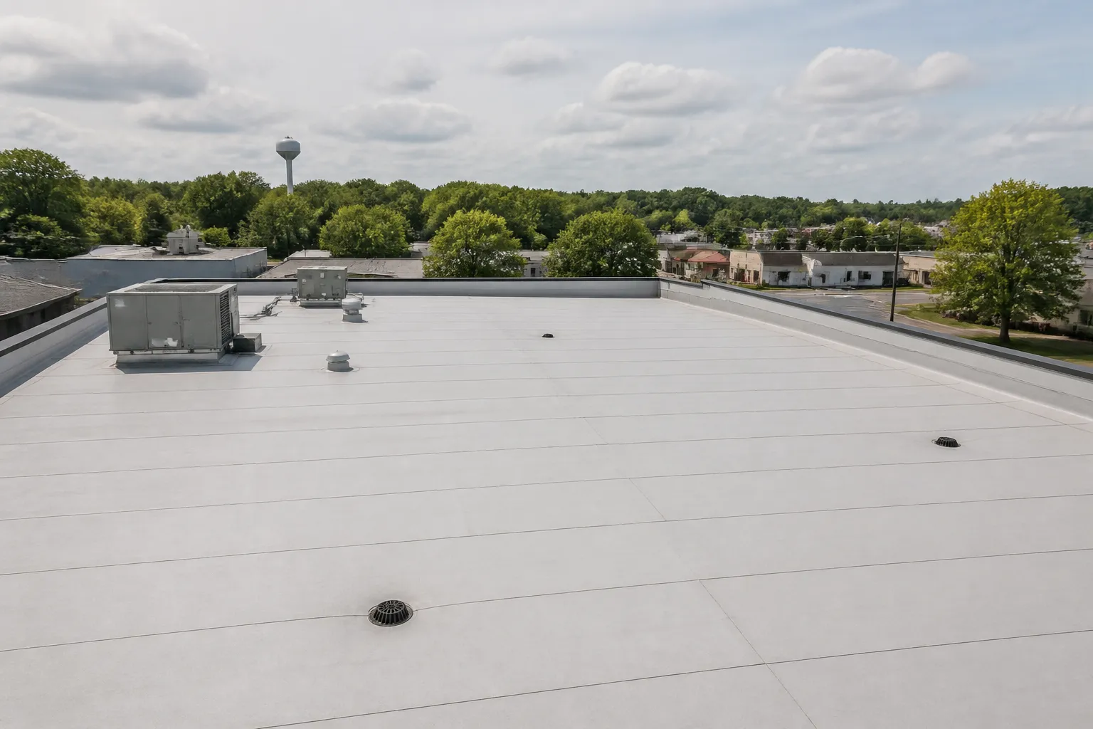 Low-slope commercial roof with membrane seams, drains, and rooftop equipment in Lowell, Arkansas
