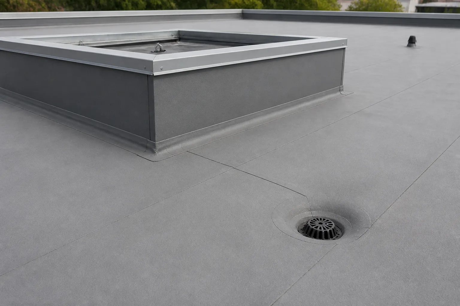 Commercial roof membrane seam and flashing around a rooftop equipment curb, with drainage nearby.