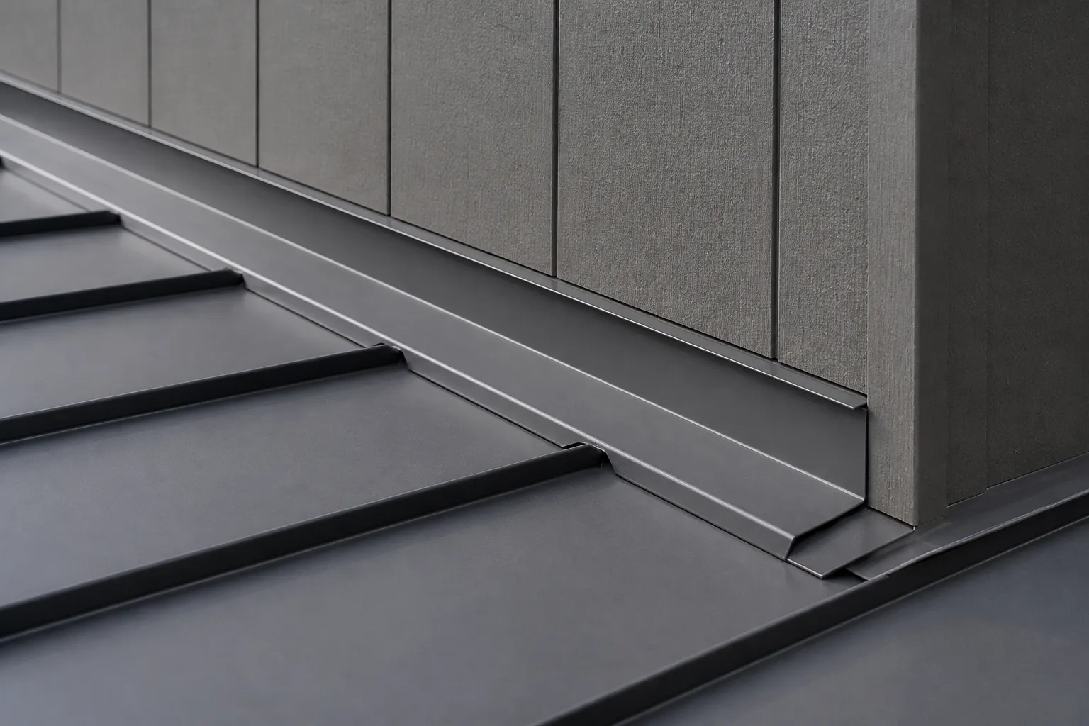 Raised standing seams meeting folded roof-to-wall flashing on charcoal metal panels