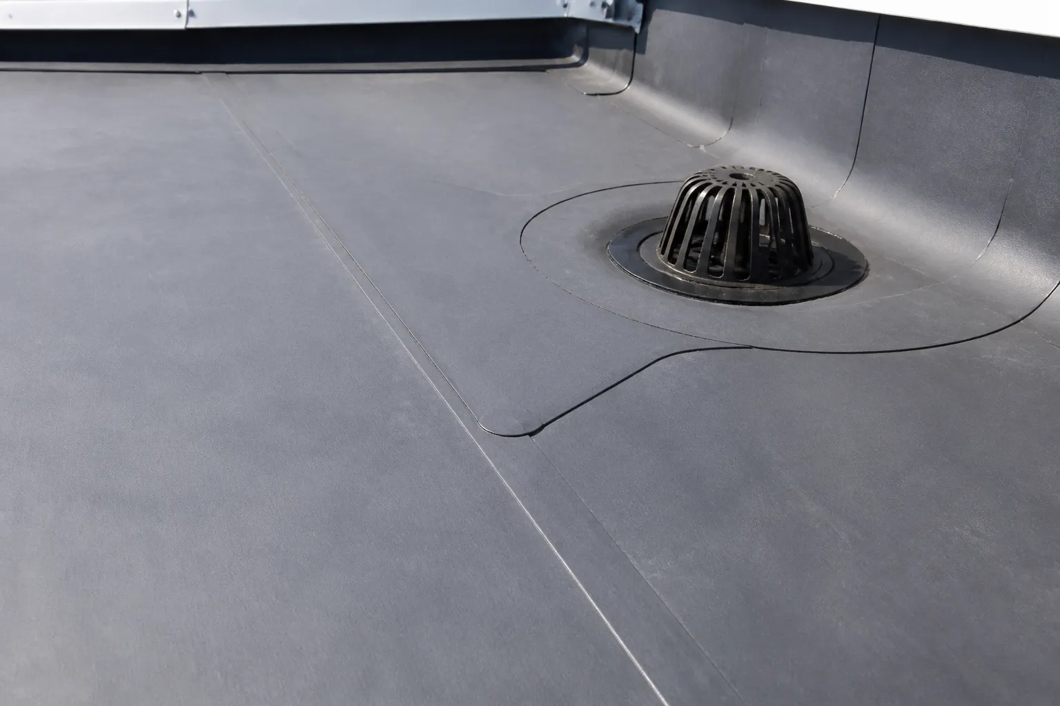 Commercial roof membrane seam and integrated drain detail on a low-slope roof